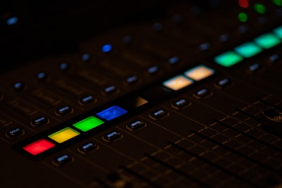 Close-up of a mixing console with colorful faders lit under studio lights.