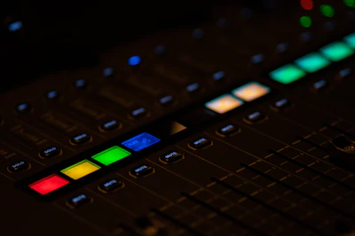 Close-up of a sleek audio mixer with colorful illuminated buttons.