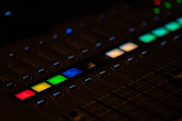 Close-up of a professional radio broadcast console with colorful buttons lit up.
