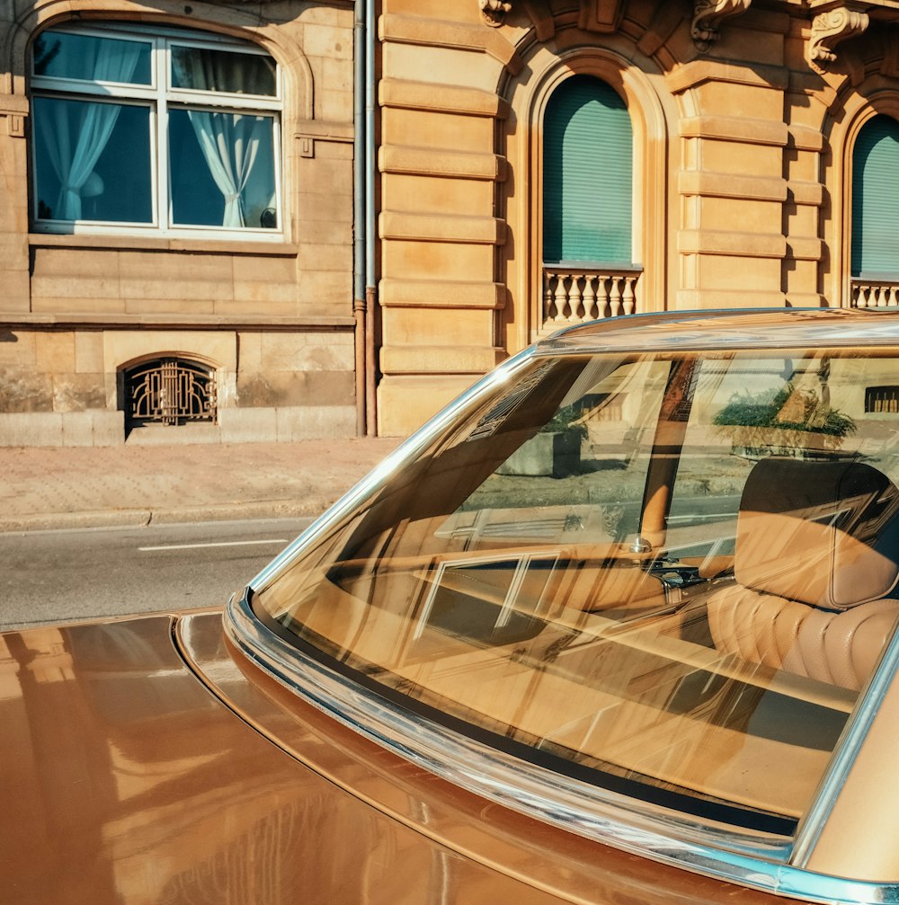 brown car parked beside brown building