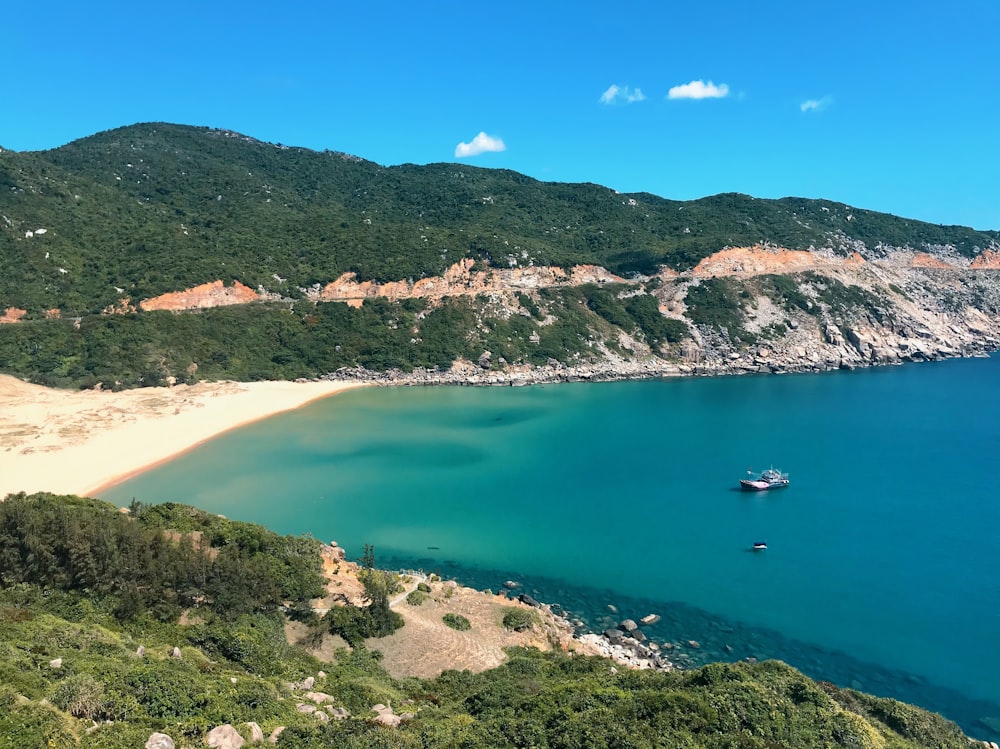 green and brown mountain beside body of water during daytime