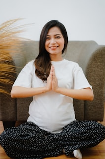woman in white button up shirt and black and white pants sitting on brown sofa