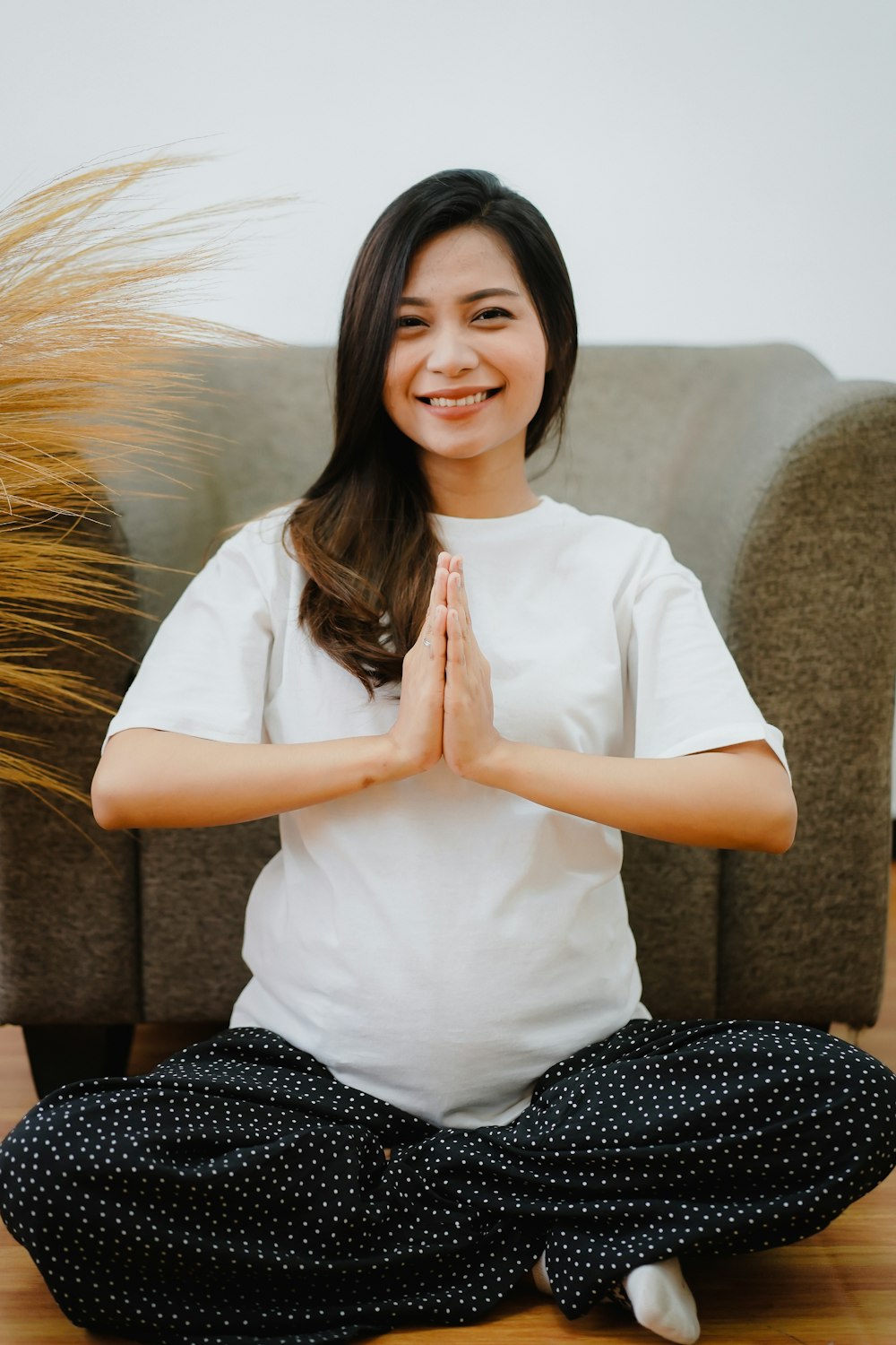 woman in white button up shirt and black and white pants sitting on brown sofa