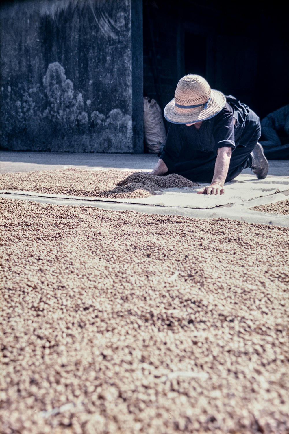 man in black t-shirt and brown hat sitting on brown sand during daytime