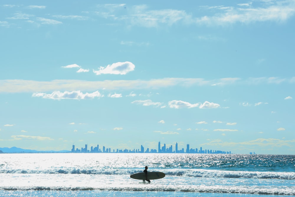 person surfing on sea waves under blue sky during daytime