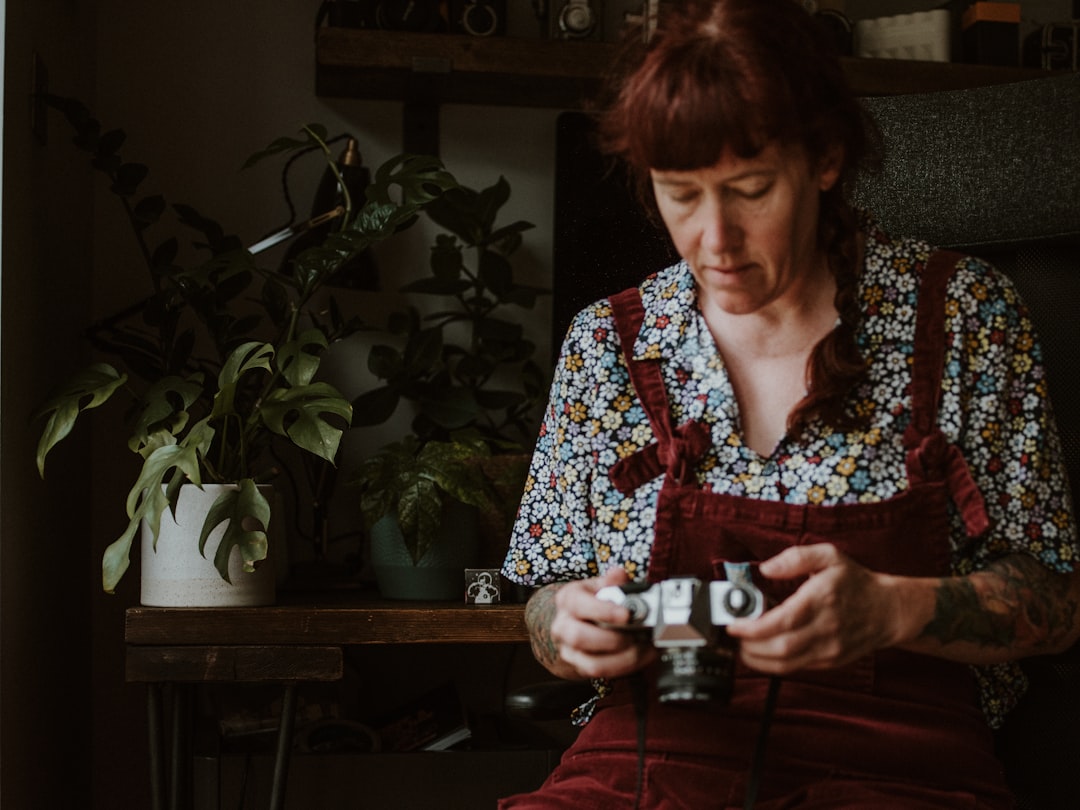 woman in black and white floral long sleeve shirt holding black and white camera