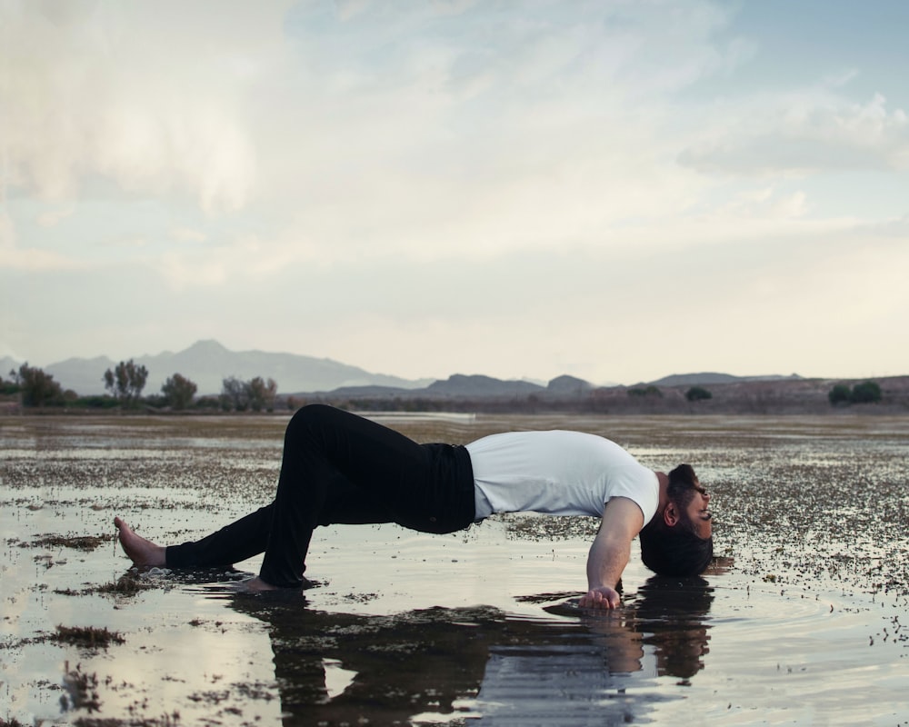 man in white t-shirt and black pants lying on water during daytime
