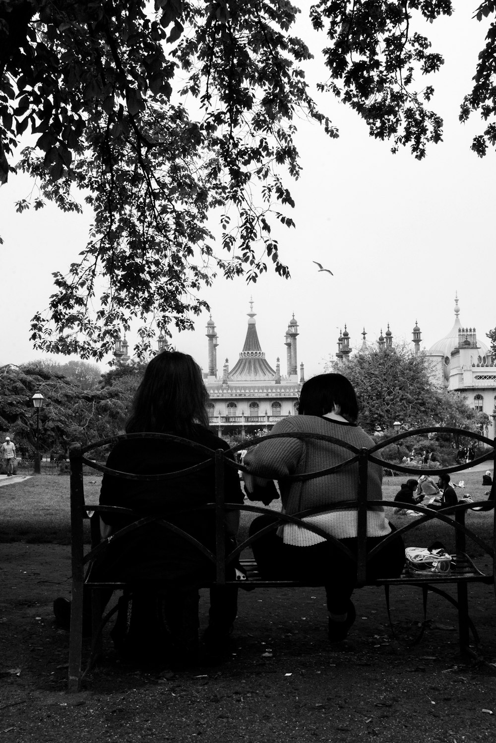 grayscale photo of 2 person sitting on bench