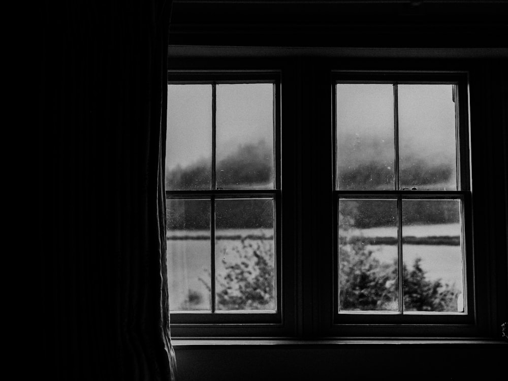 カーテン付き窓のグレースケール写真