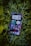 A smartphone displaying a variety of apps is resting on a bed of green leaves. The screen shows multiple applications, including music, messaging, and time tracking, all organized neatly.