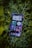 A smartphone displaying a variety of apps is resting on a bed of green leaves. The screen shows multiple applications, including music, messaging, and time tracking, all organized neatly.