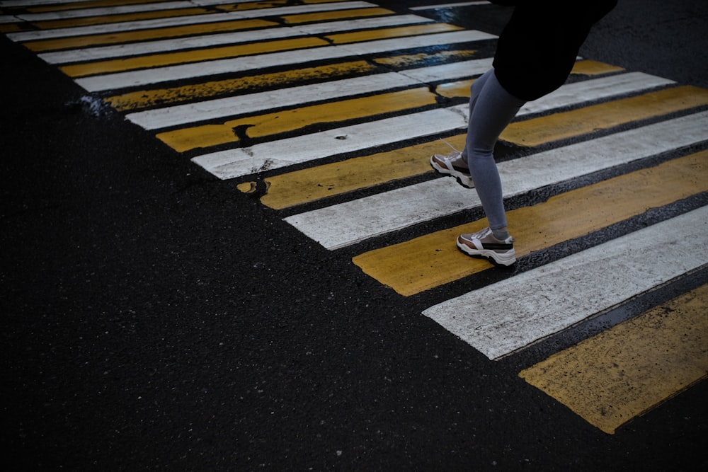 person in black pants and white sneakers standing on pedestrian lane