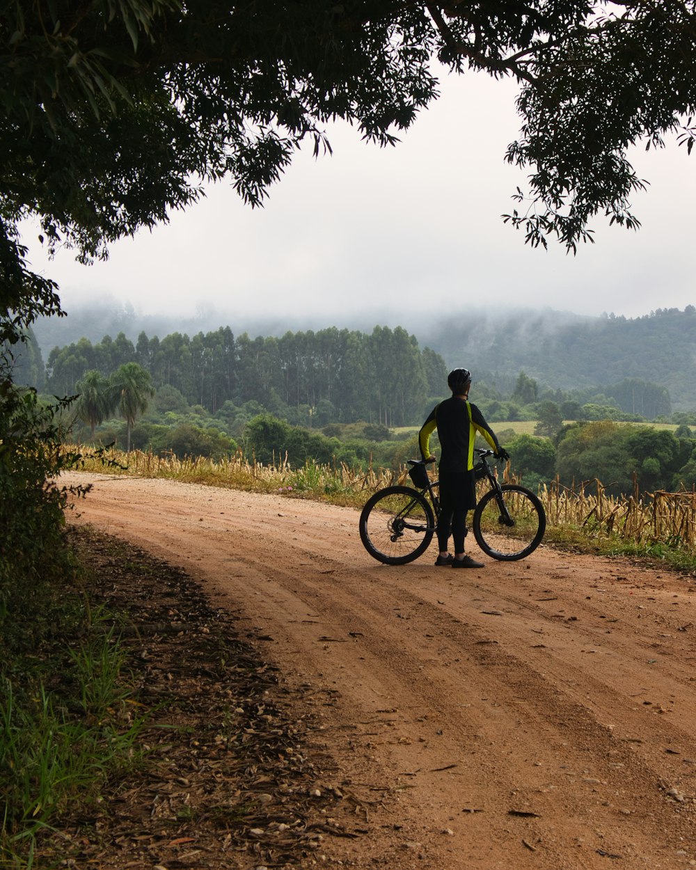 um homem com uma bicicleta em uma estrada de terra