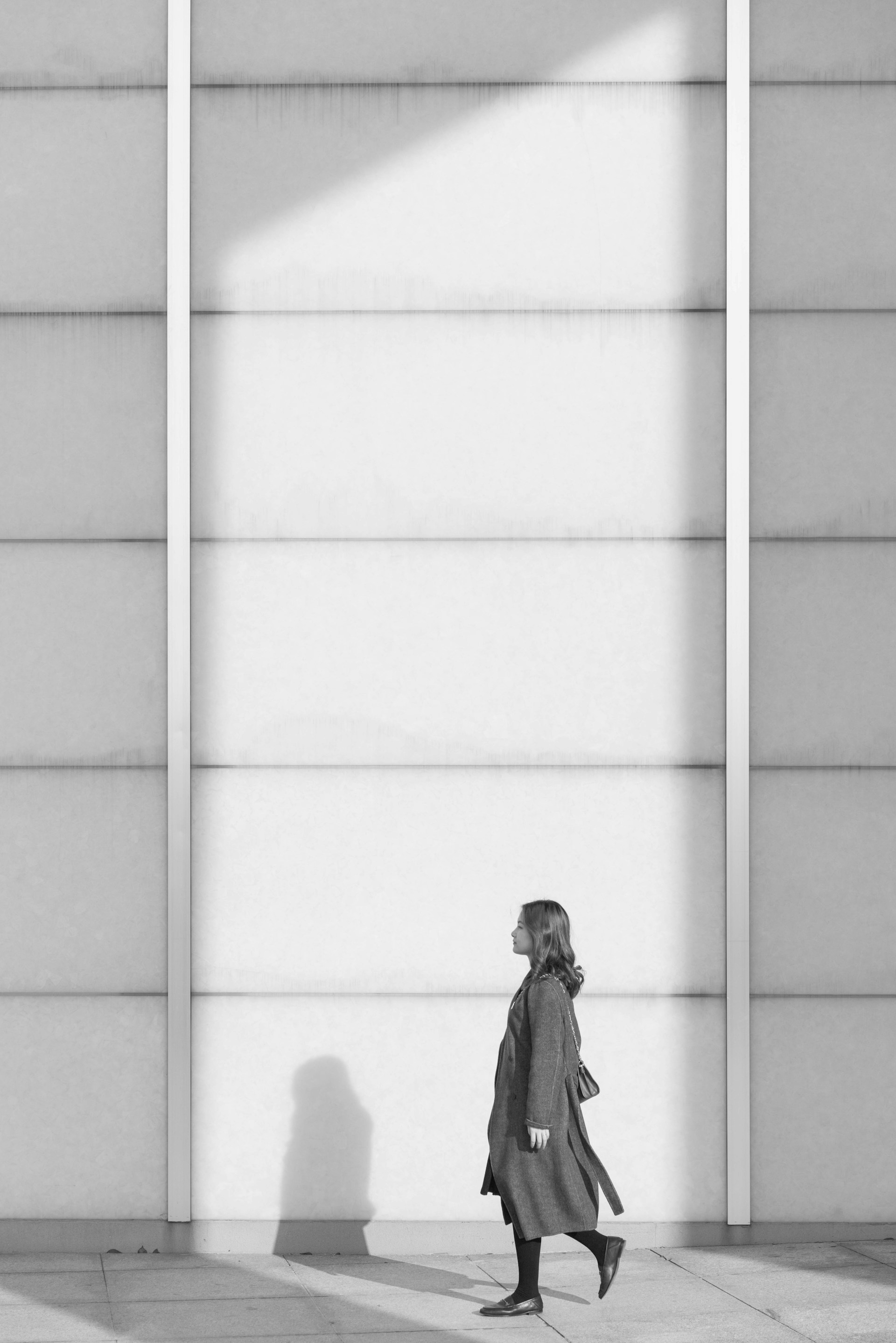 woman in black jacket standing in front of white and gray wall