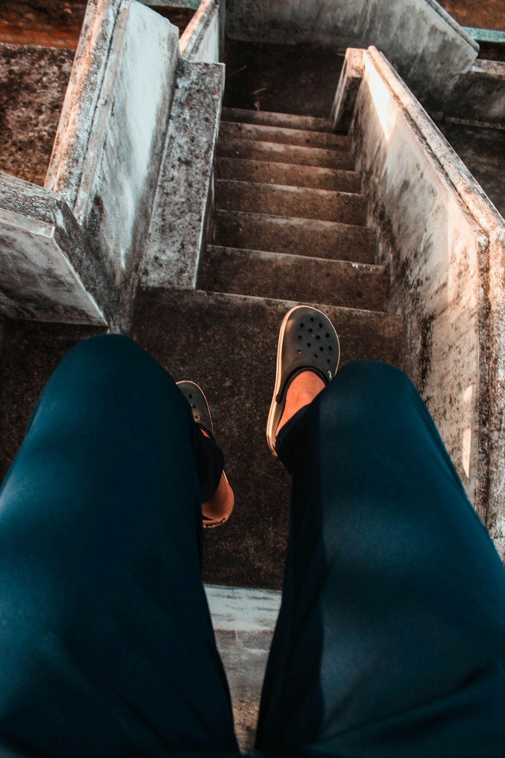 person in blue pants wearing brown rubber clogs