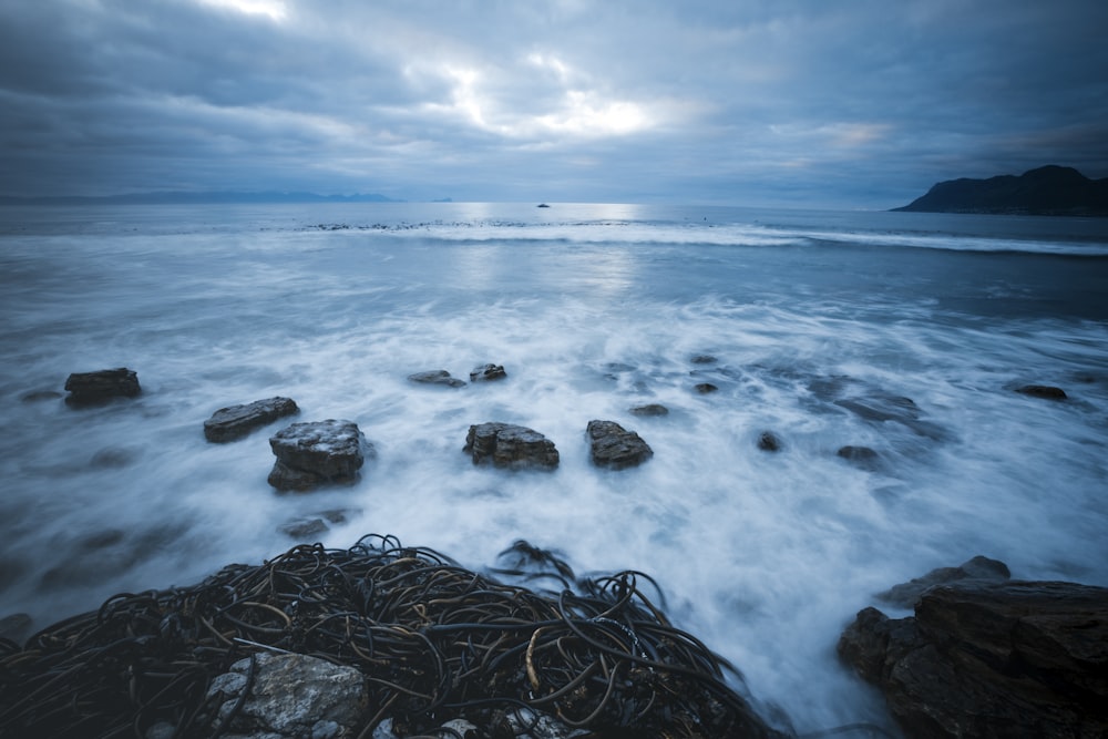 brown rock formation on sea under white clouds during daytime