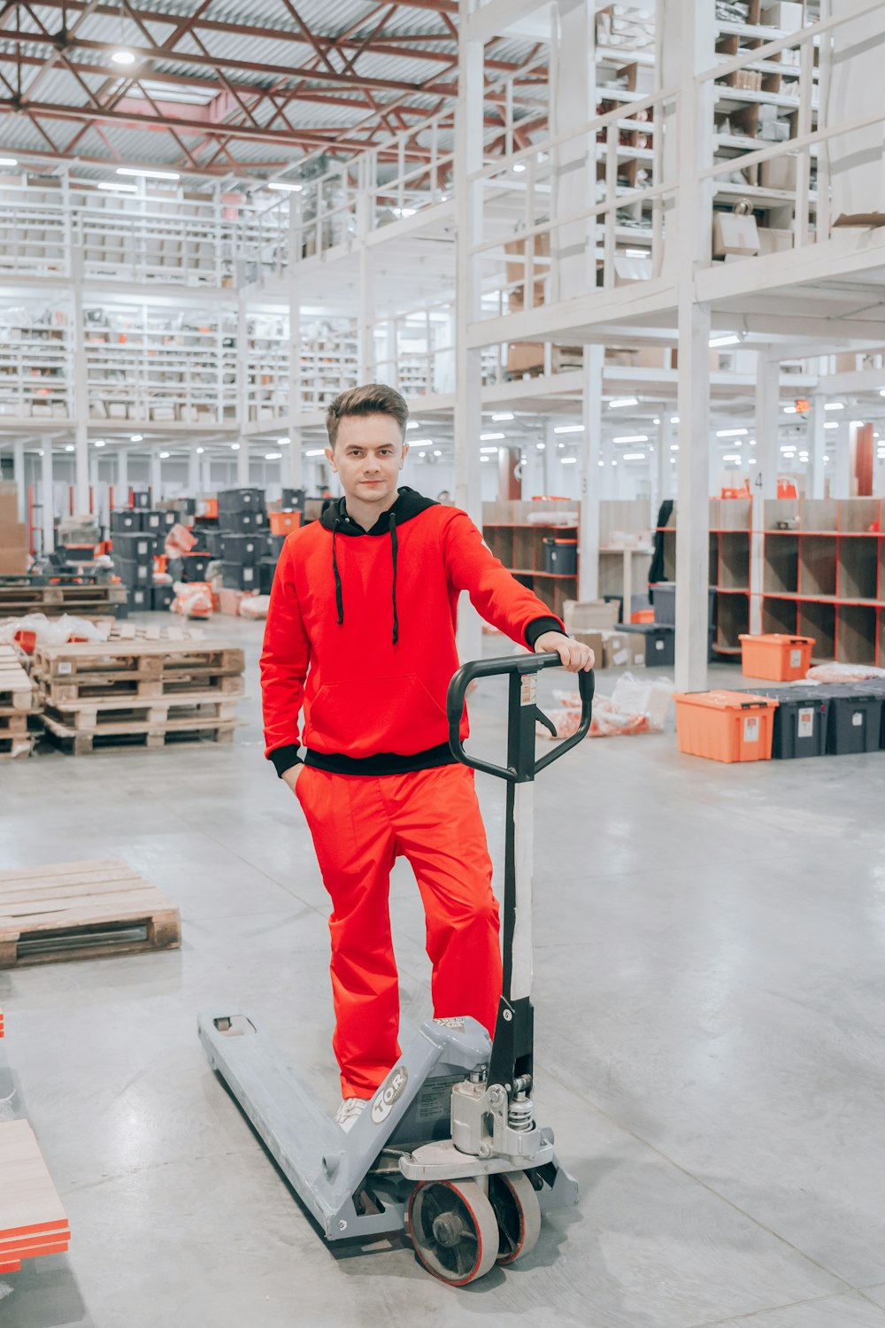 man in red sweater and black pants holding red and black hand truck