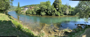 A serene river scene with clear water, healthy vegetation on the banks, and a local community working together to protect and restore the watershed.