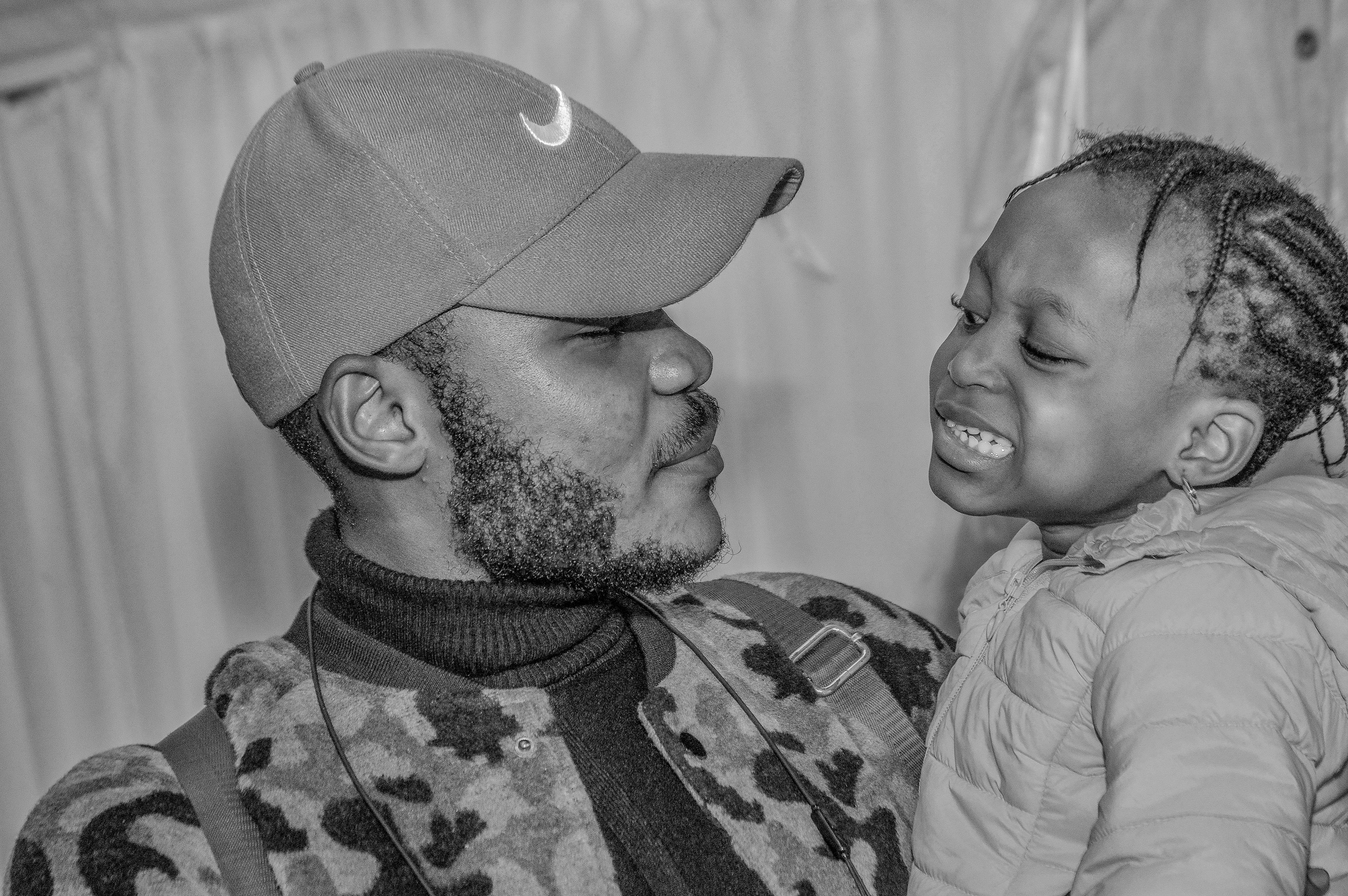 man in camouflage shirt carrying girl in grayscale photography