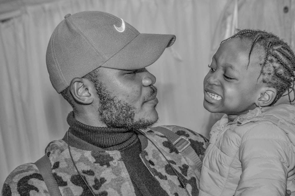 man in camouflage shirt carrying girl in grayscale photography