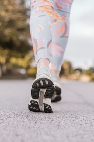 Close-up of a runner's legs wearing sleek, breathable leggings on a sunlit trail.