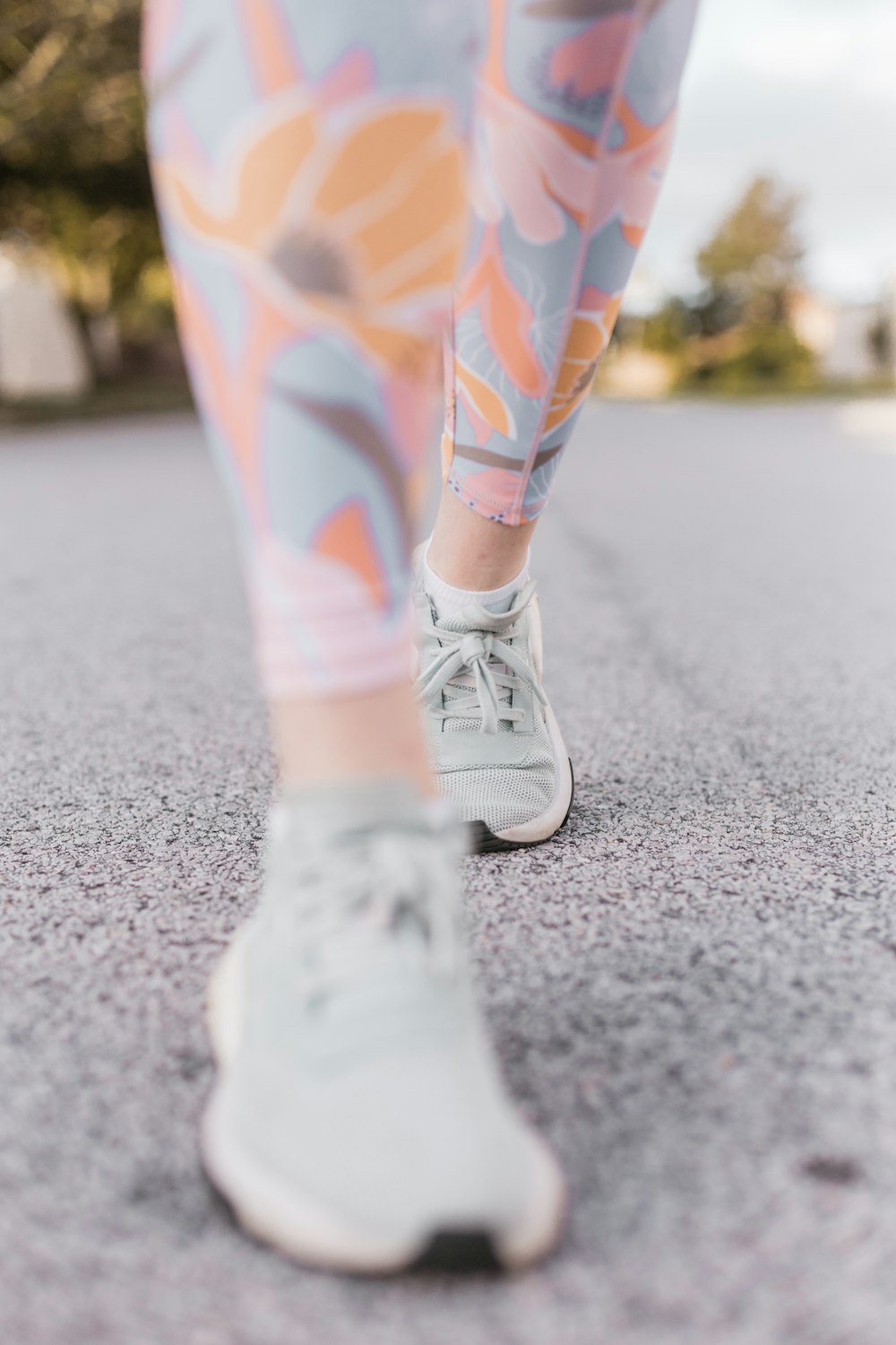 Person in weißen und orangefarbenen Hosen trägt weiße Nike-Turnschuhe