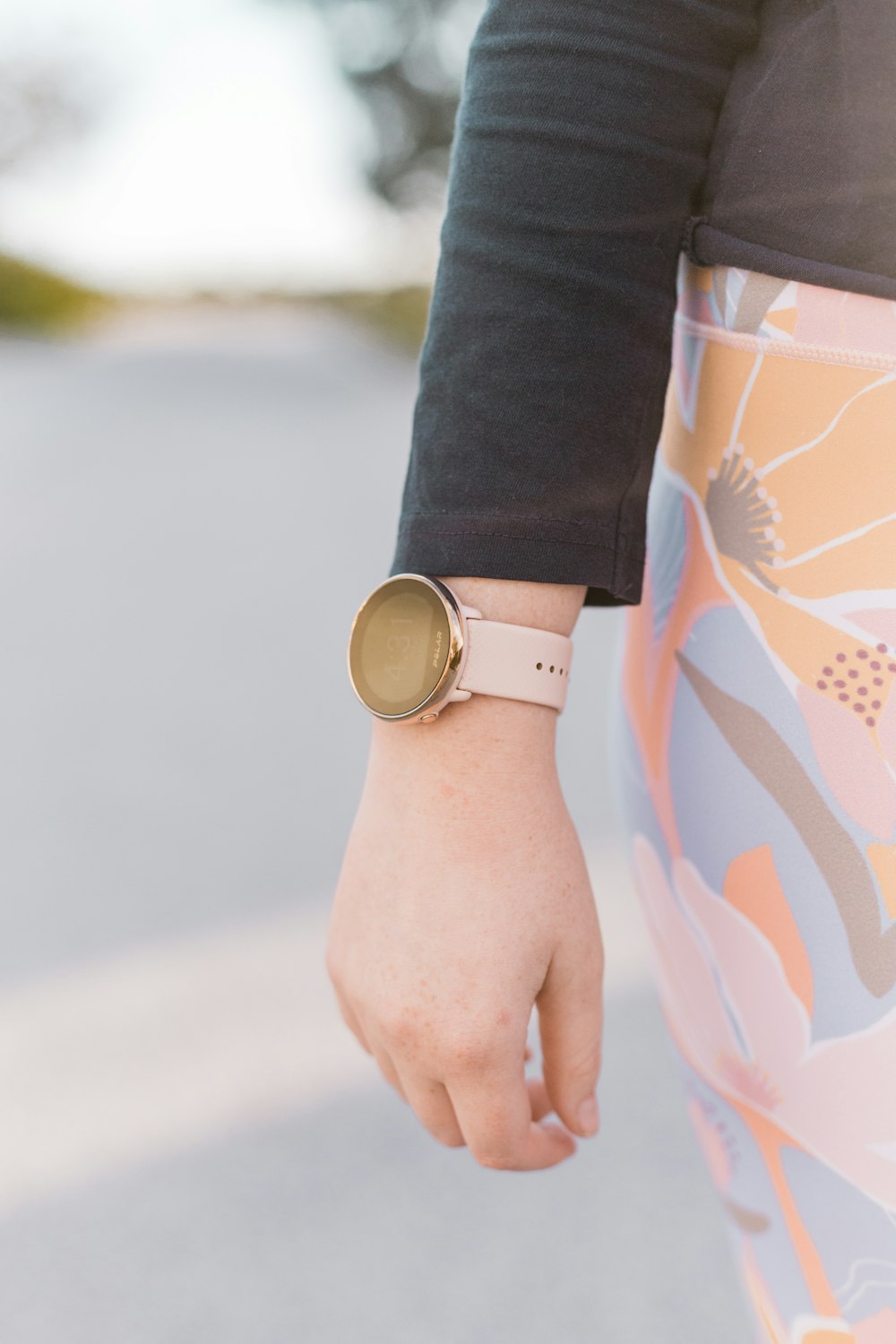 person wearing gold round analog watch with brown leather strap