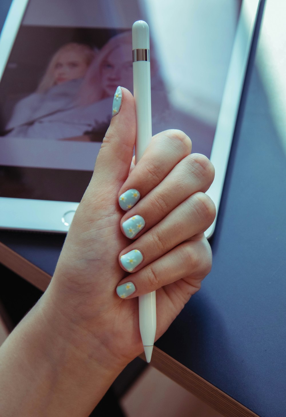 person with teal manicure holding white tablet computer