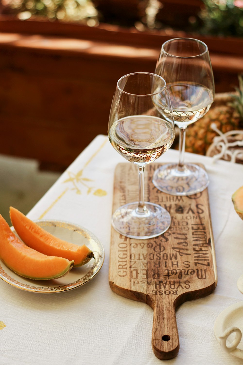 sliced orange fruit on brown wooden chopping board beside clear wine glass