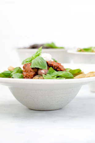 A vibrant bowl of homemade pasta with tomato sauce and basil, styled with fresh ingredients around.