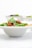 A bowl filled with fresh basil leaves, dollops of creamy white sauce, and a rich red tomato-based sauce, possibly pasta or a similar dish. The focus is on the vibrant colors and textures of the ingredients.