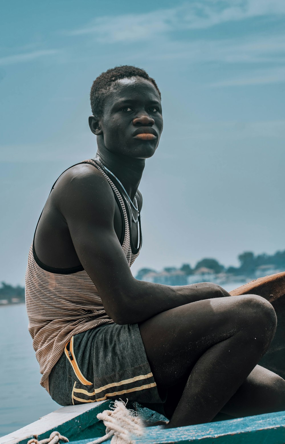 man in black tank top sitting on brown chair during daytime