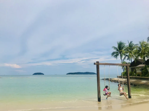 Children playing on a sunny beach with turquoise waters and palm trees swaying gently.