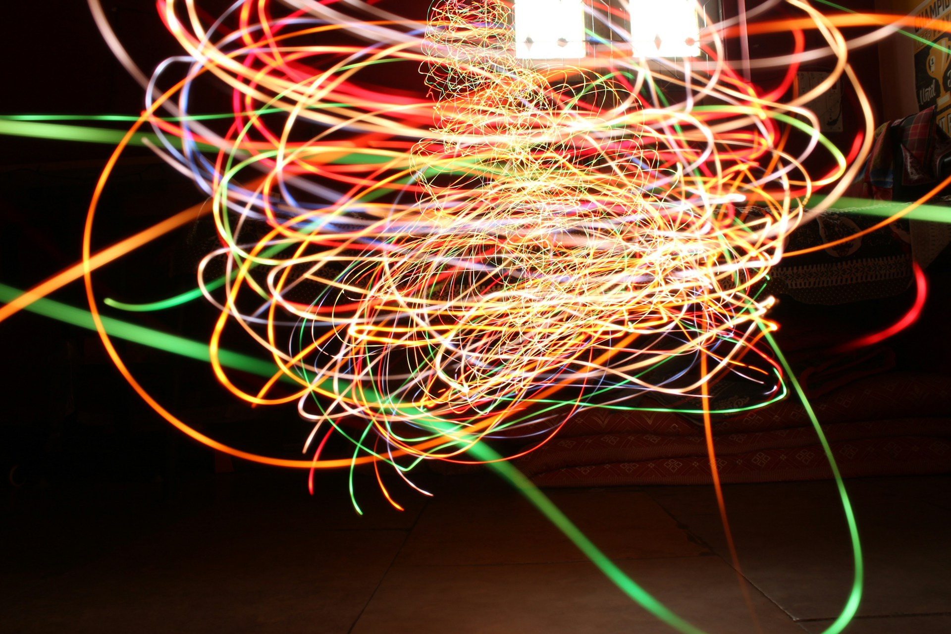 A vibrant, colorful abstract swirl with dynamic light trails and subtle chart lines glowing in the background.