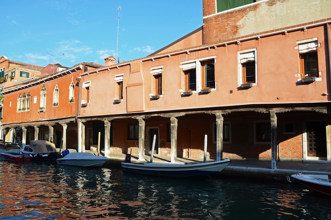 blue and white boat on water near brown concrete building during daytime