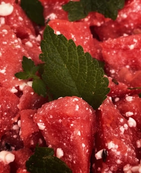 Chunks of juicy watermelon are mixed with small curd-like pieces, possibly feta or cottage cheese, and garnished with fresh mint leaves.