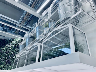 An industrial-style metal vessel with clean lines, featuring a cluster of green plants on a modern office desk.
