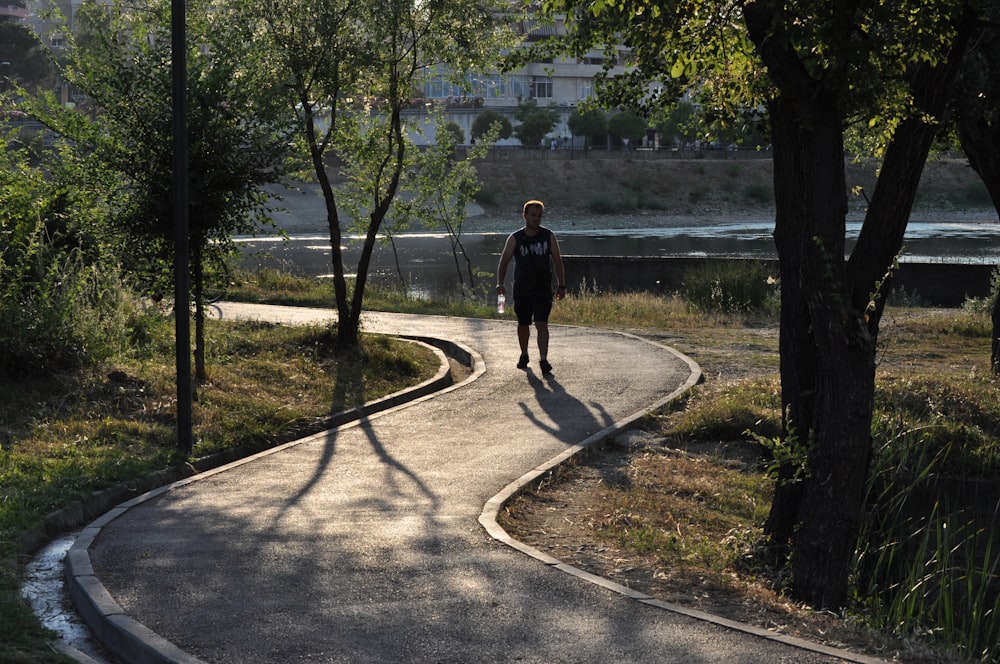 man in black jacket walking on gray concrete road during daytime