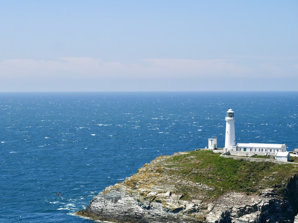 white lighthouse on cliff by the sea during daytime