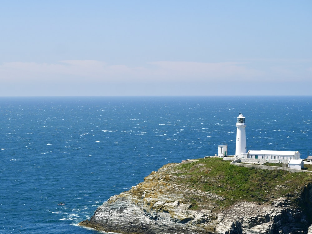 Phare blanc sur la falaise au bord de la mer pendant la journée