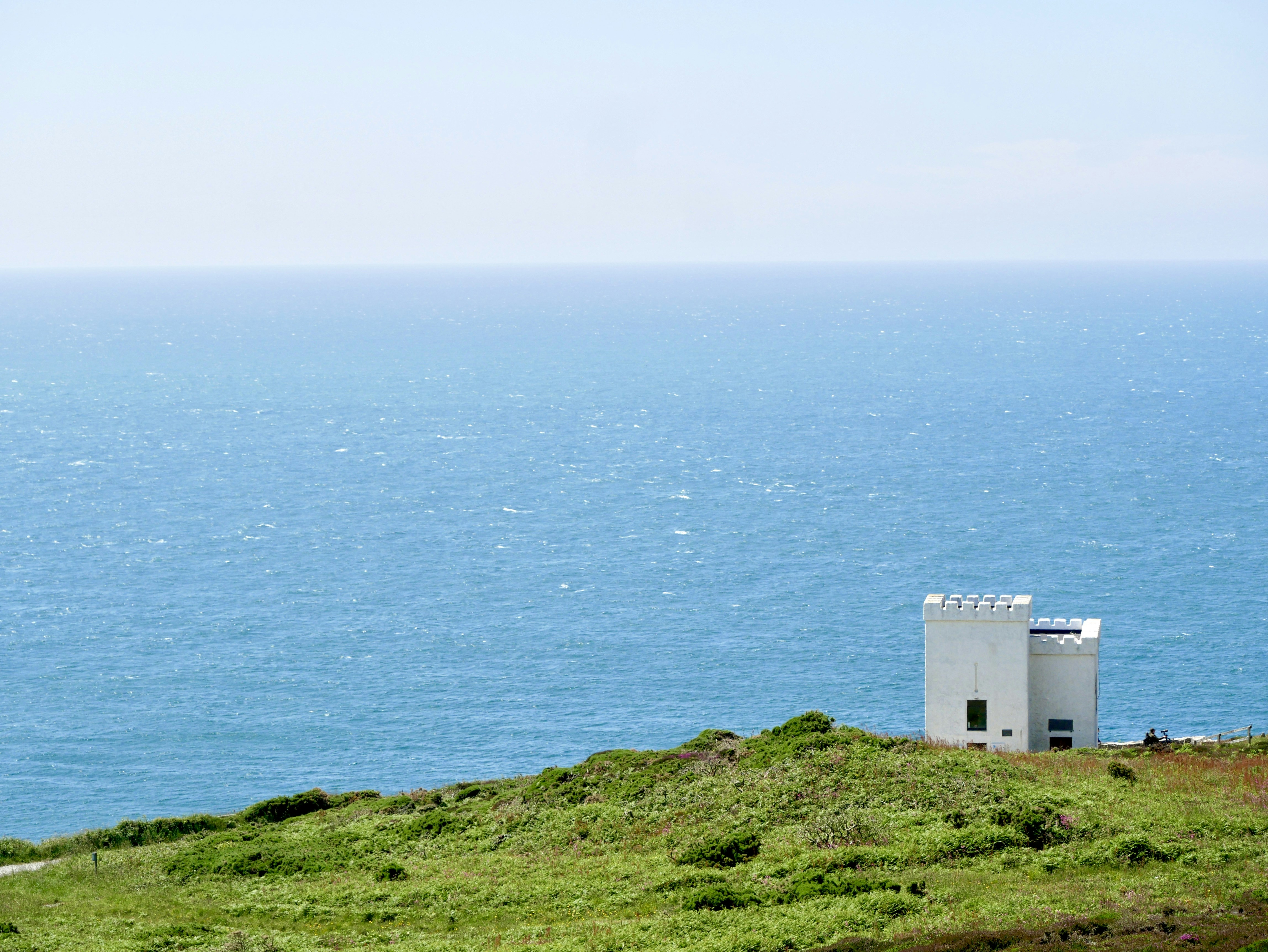 white concrete building on green grass field near body of water during daytime