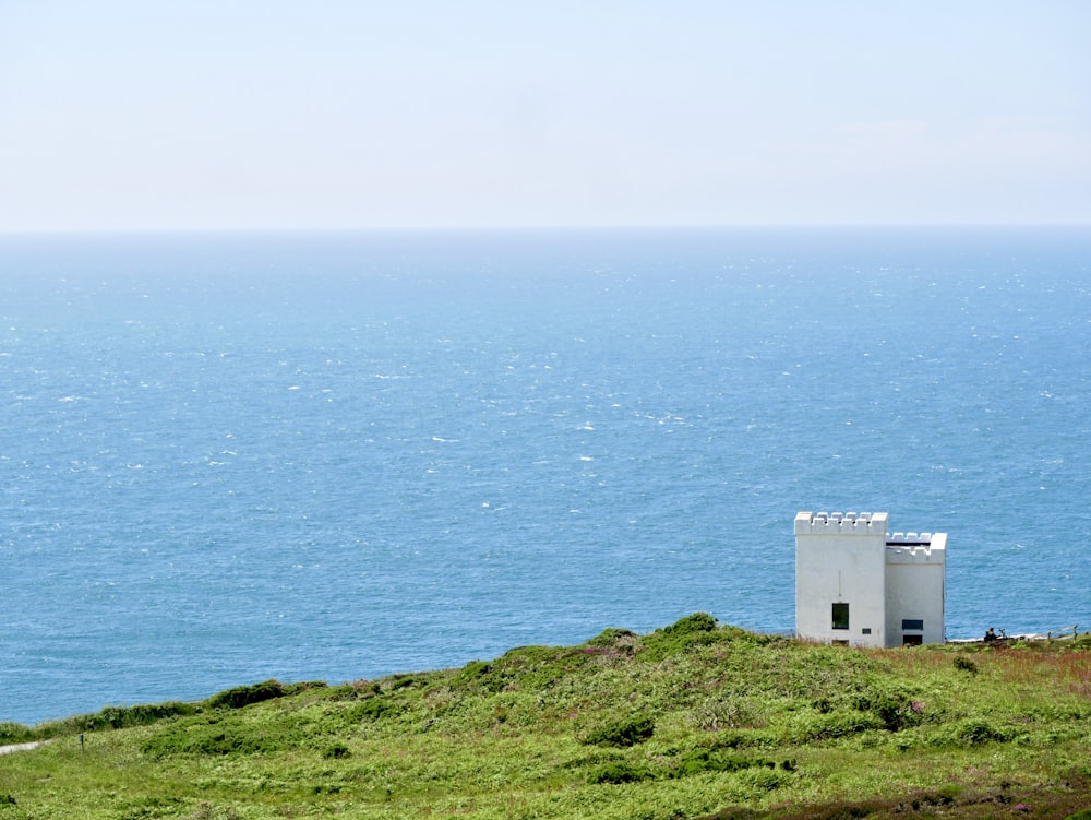 Bâtiment en béton blanc sur un champ d’herbe verte près d’un plan d’eau pendant la journée