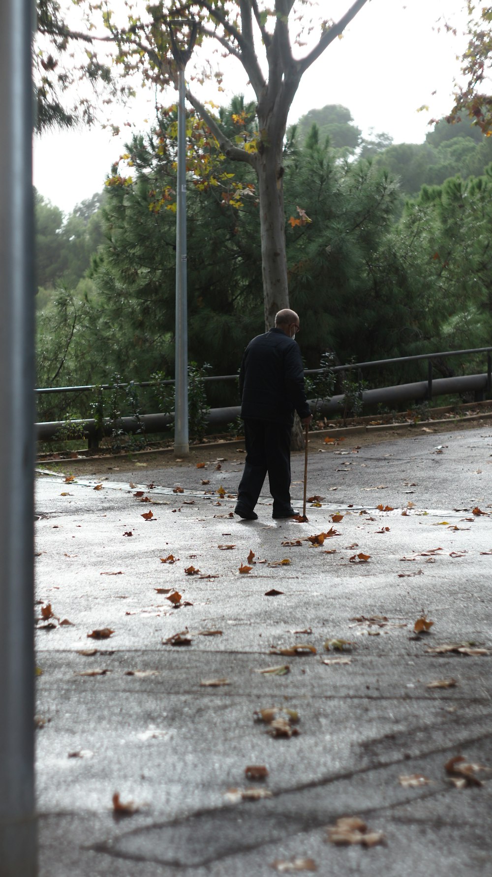 homem em jaqueta preta andando no caminho cinza durante o dia