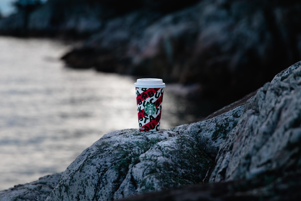white red and blue disposable cup on gray rock