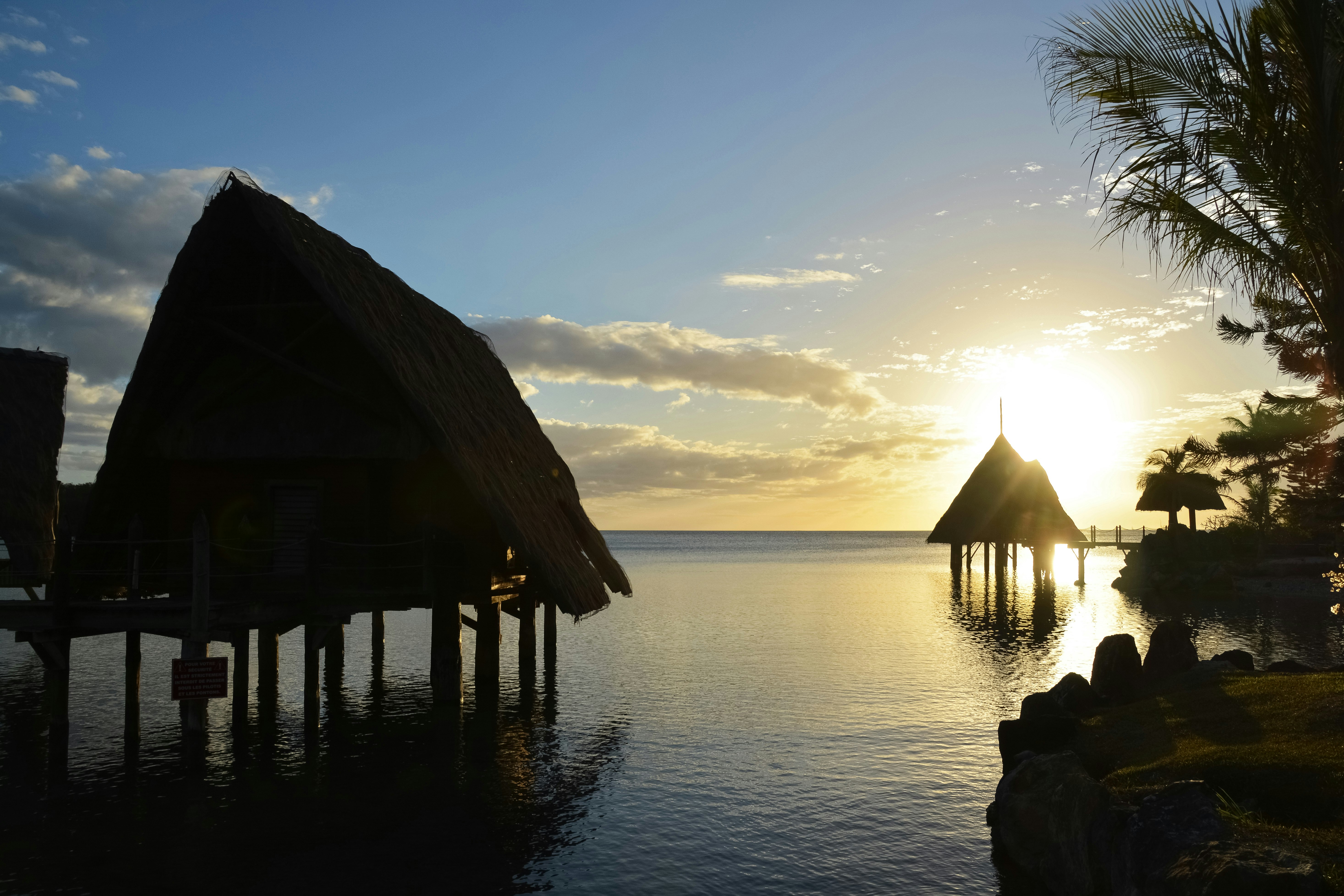 brown wooden house on body of water during sunset