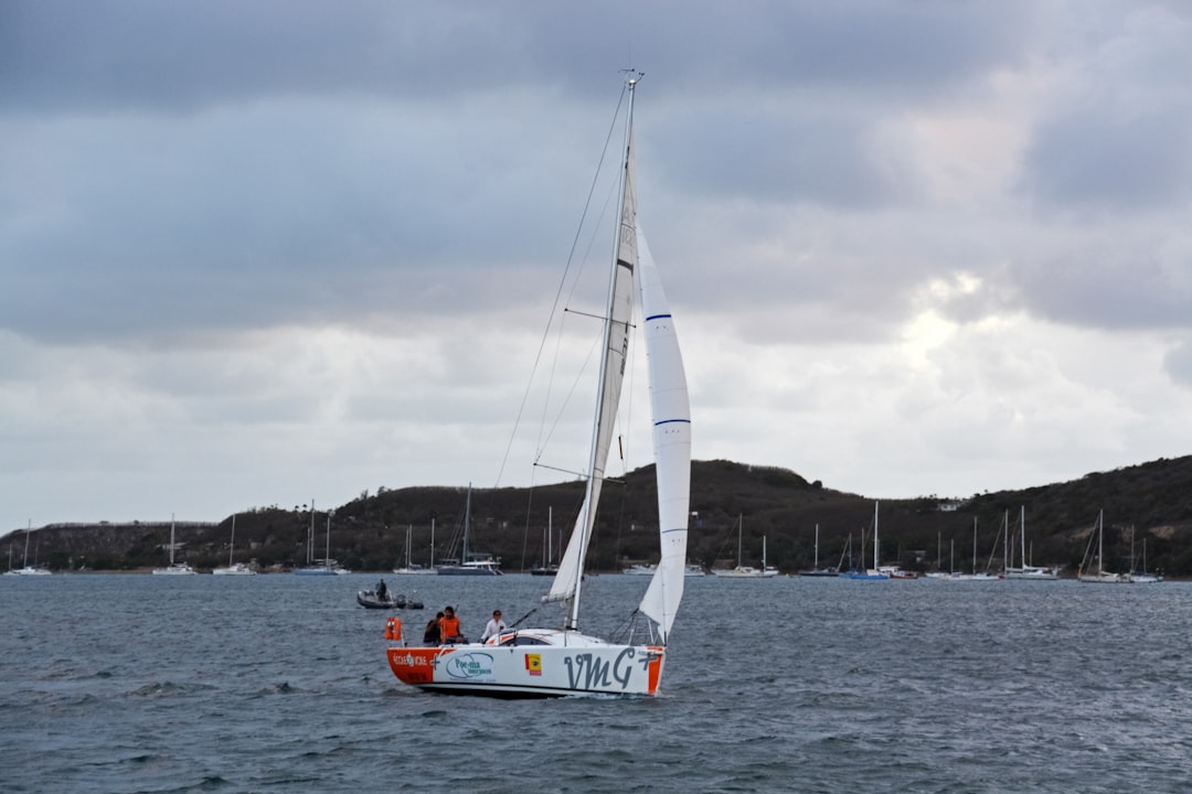 white sail boat on sea under gray sky