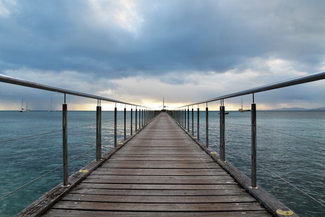 brown wooden dock on sea under white clouds during daytime