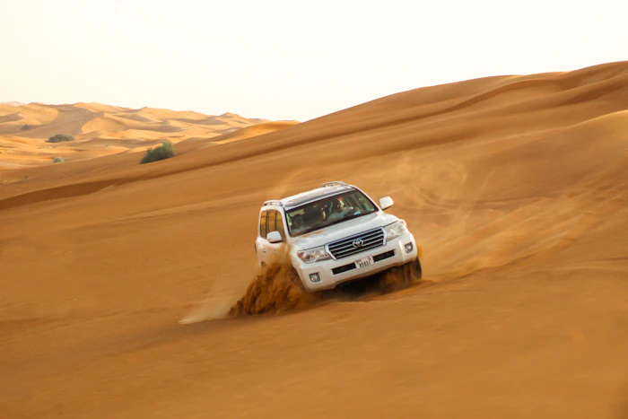 White 4x4 vehicle parked on red desert sand