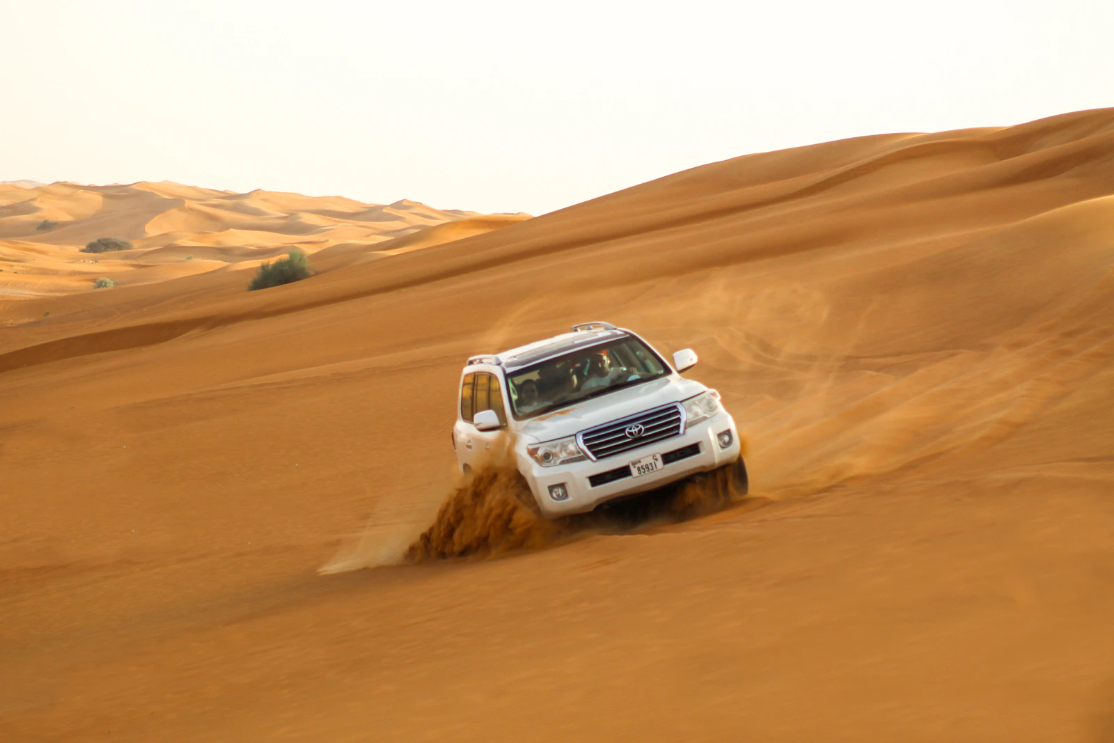 White 4x4 cresting a sand dune in the Dubai desert