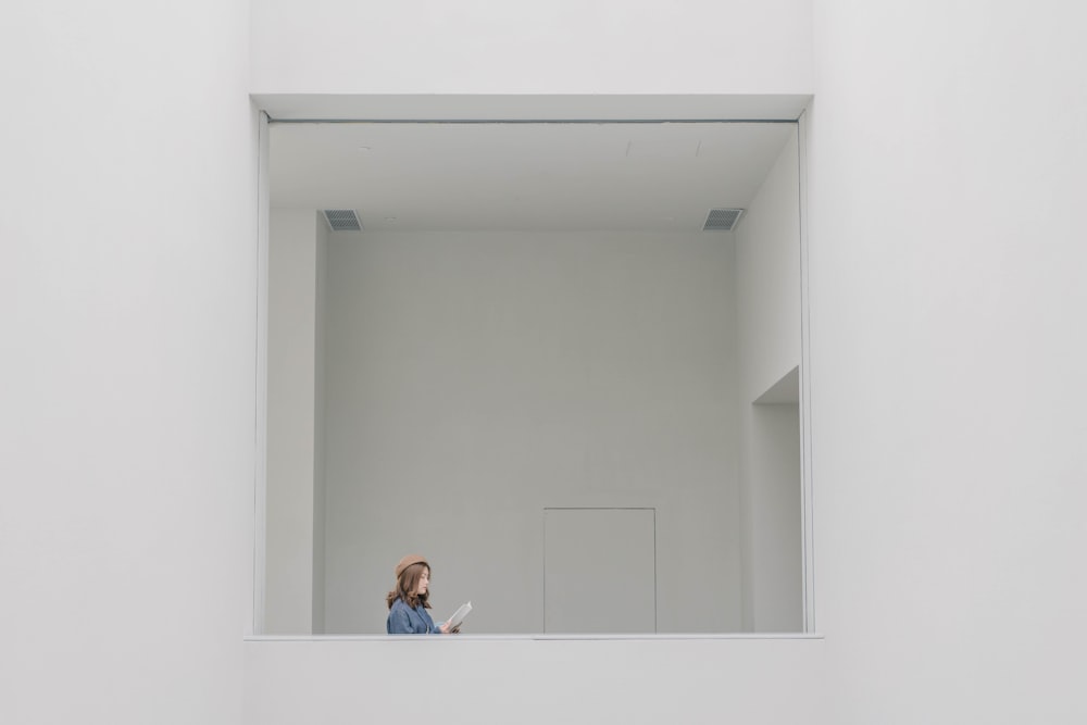 Femme en chemise à manches longues bleue assise sur un mur de béton blanc